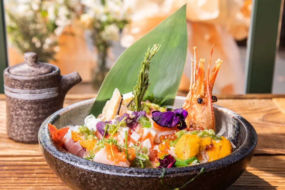 Kiroro-Japanese-restaurant-Seafood-Sashimi-Bowl-CA Seafood Sashimi Bowl features assorted fresh sashimi, colorful toppings, and edible flowers on rice, served in a ceramic bowl at Kiroro, a Japanese restaurant in CA